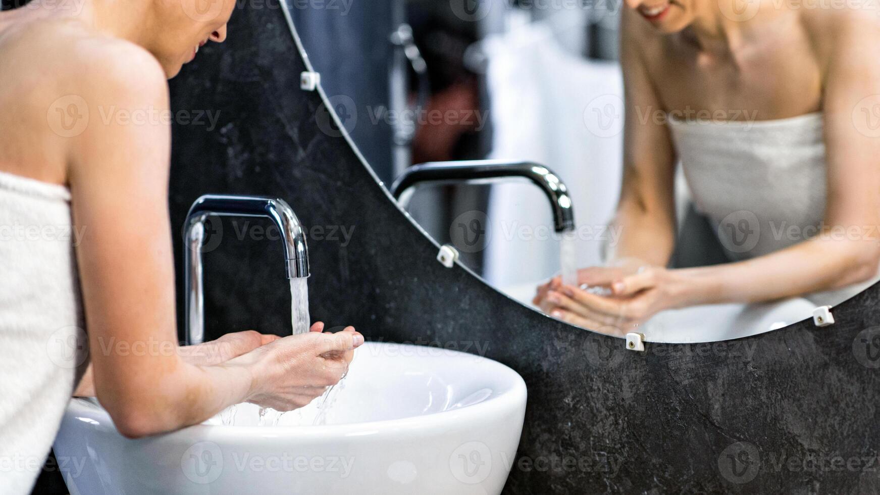 Hygiene Routine. Mature Lady Washing Face Standing Wrapped In Towel In Bathroom At Home. Selective Focus photo