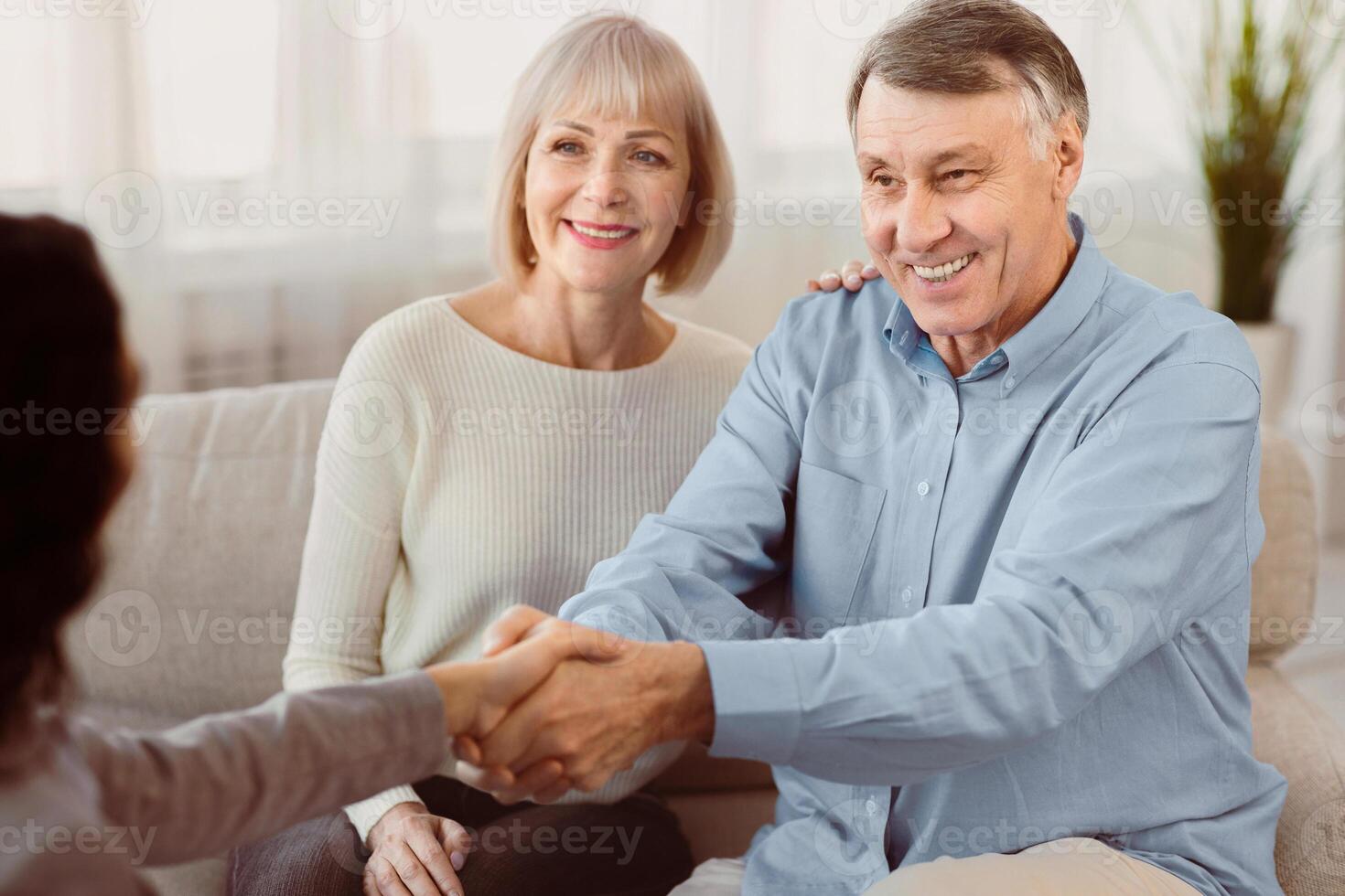 Nice To Meet You. Young female therapist meeting elderly couple for a counselling session, greeting with handshake photo