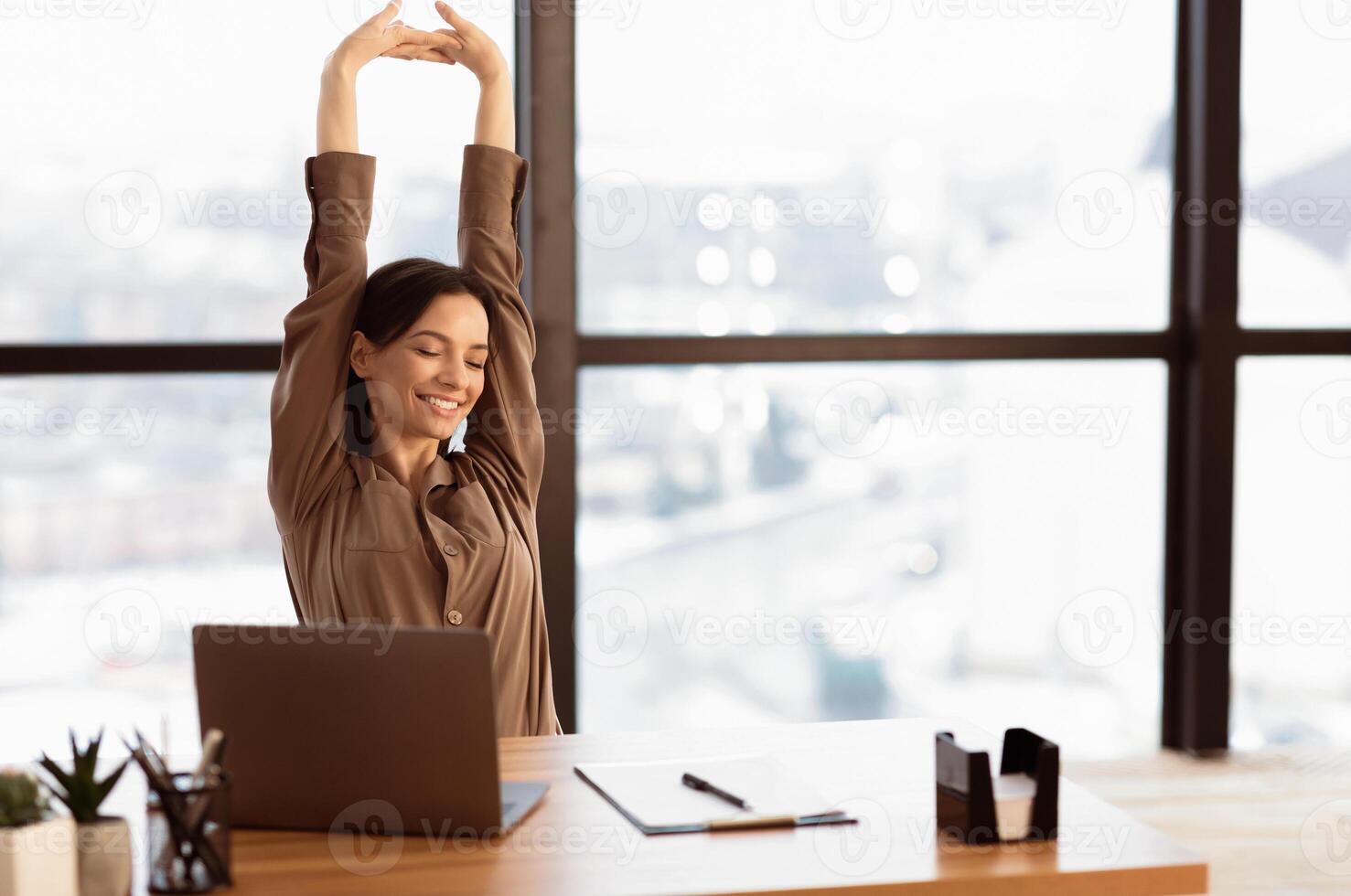Good Morning. Happy female manager stretching her body and arms working at home or modern office, copyspace photo
