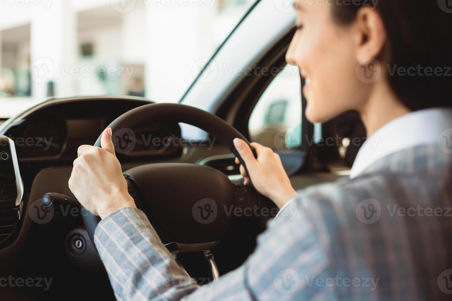 Driving Alone. Unrecognizable woman testing a car, rear view over the shoulder, selective focus on steering wheel photo