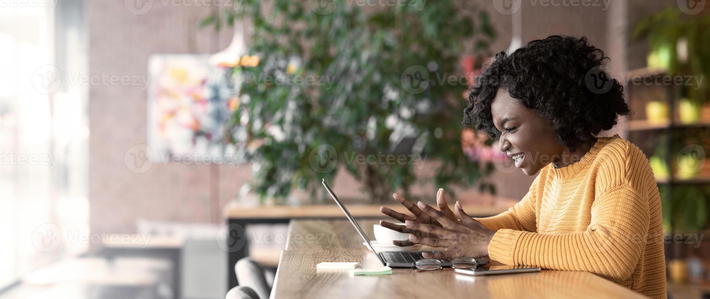 Writer's block. Angry afro girl blogger screaming at laptop screen, working at cafe, copy space photo