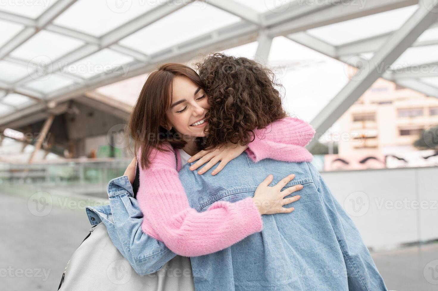 Two friends share a heartfelt embrace in a contemporary, well-lit environment, showcasing their joy and connection. The moment reflects a deep bond between them. photo