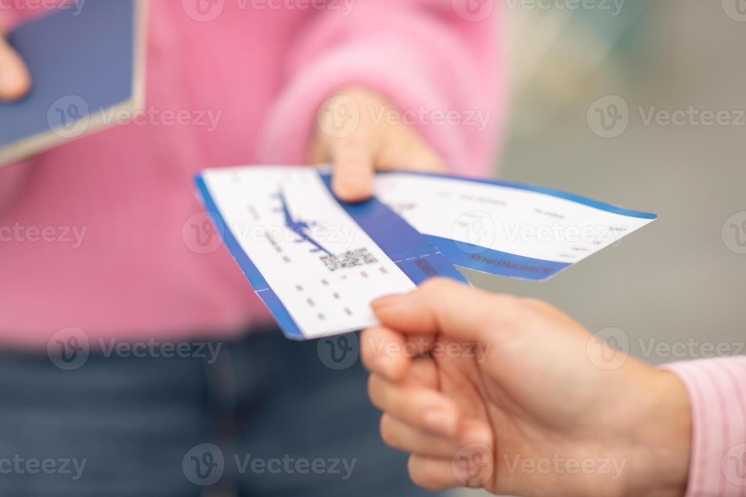 Two travelers hand over their boarding passes while holding passports at an airport check-in counter. The moment captures anticipation and excitement for their journey ahead. photo