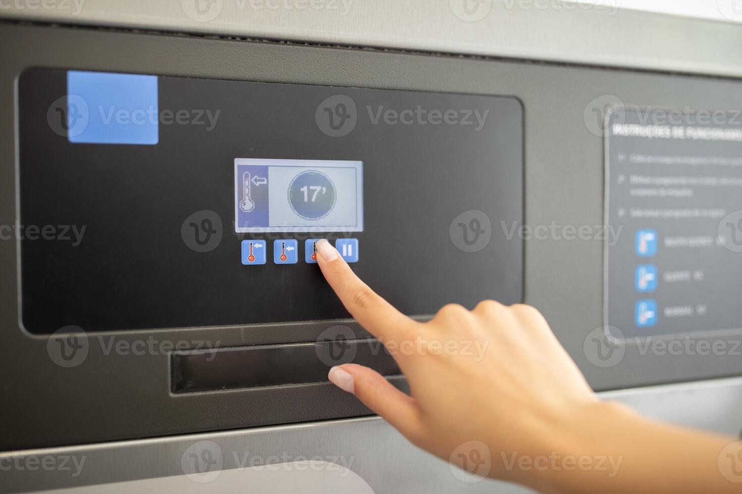 A person is pressing buttons on a touch screen control panel, likely adjusting settings in a facility. The interface displays temperature and additional options clearly. photo