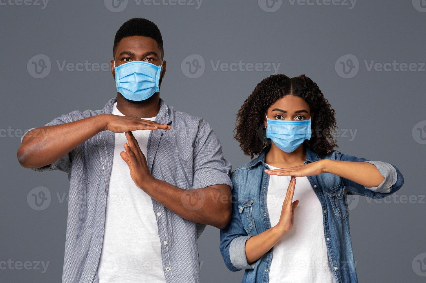 Quarantine Time Concept. Young Black Couple In Protective Medical Masks Showing Time-Out Gesture While Standing Over Light Background In Studio photo