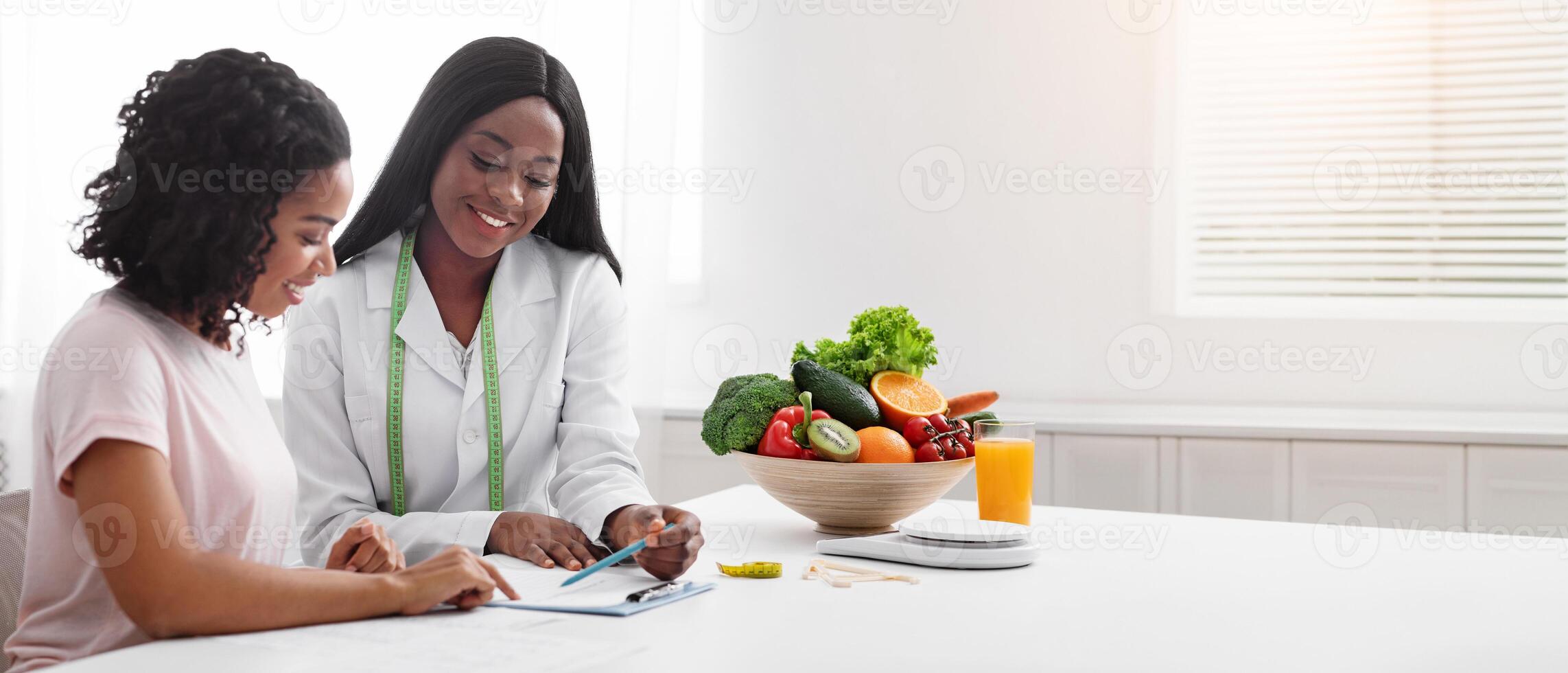 African ladies doctor and patient having conversation according treatment in modern clinic, copy space photo