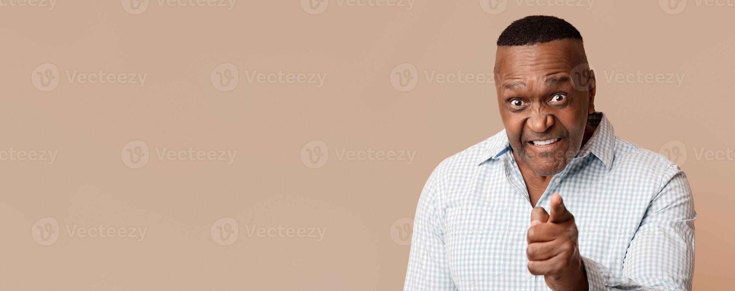Its your fault. Angry middle aged african american man pointing at camera, blaming you, orange studio background photo