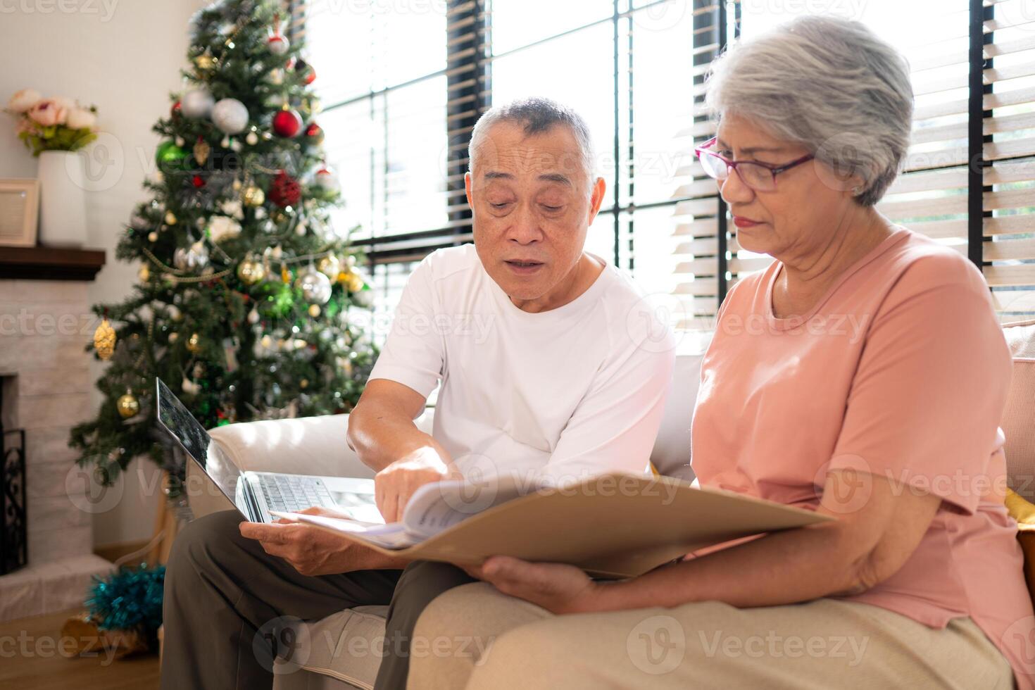 Grandfather and grandmother are reviewing the expenses and the food menu to host their children and grandchildren during the Christmas holiday at home photo