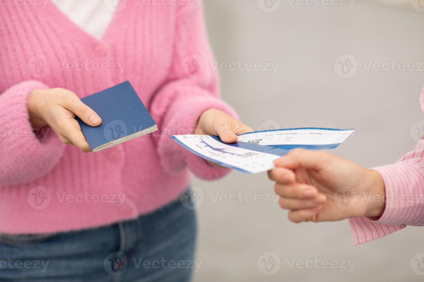 A traveler hands over a blue passport and travel tickets at an airport check-in. This busy moment captures the excitement of beginning a journey at a bustling airport. photo