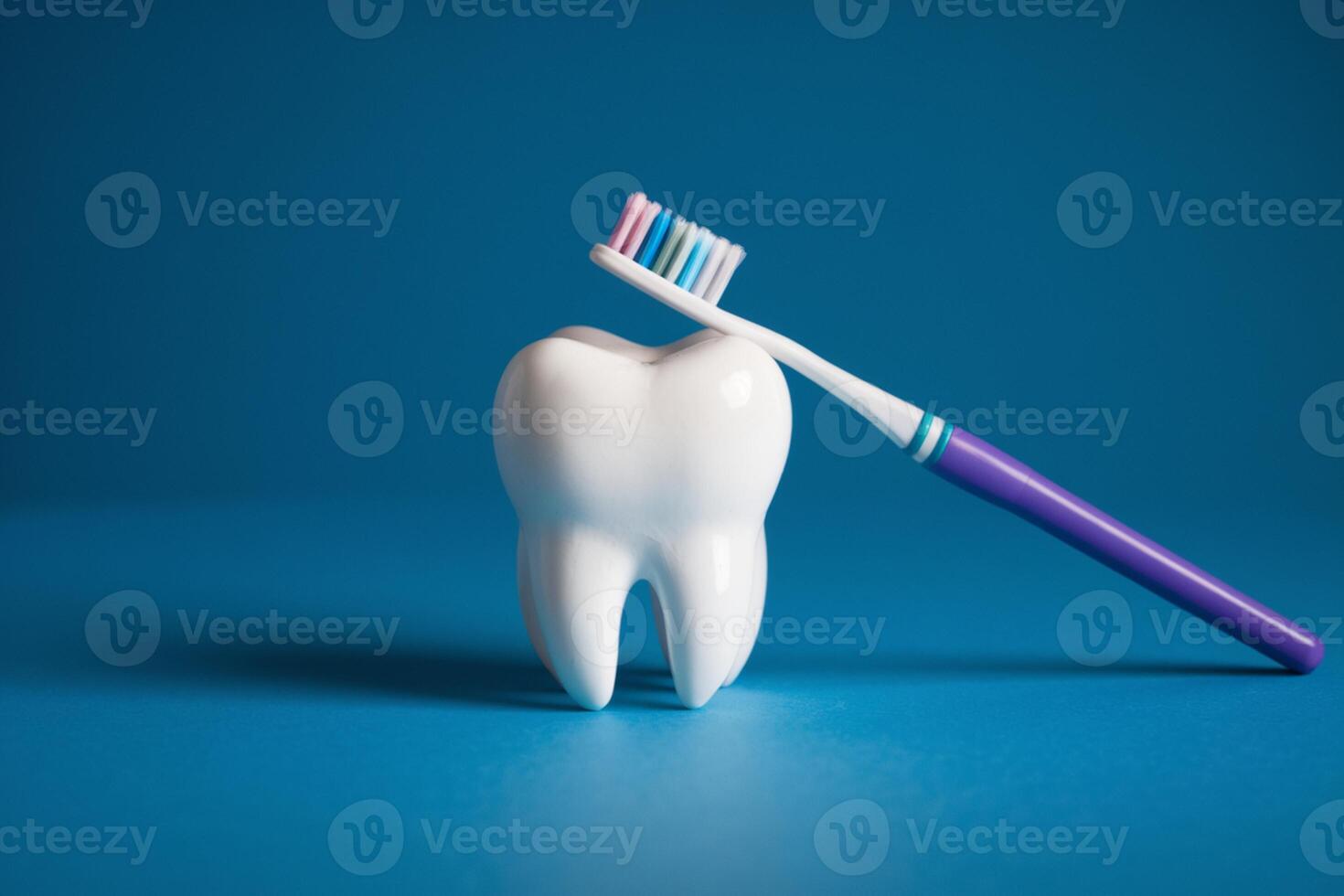 Tooth centered on blue surface with toothbrush leaning against it, bristles upward photo