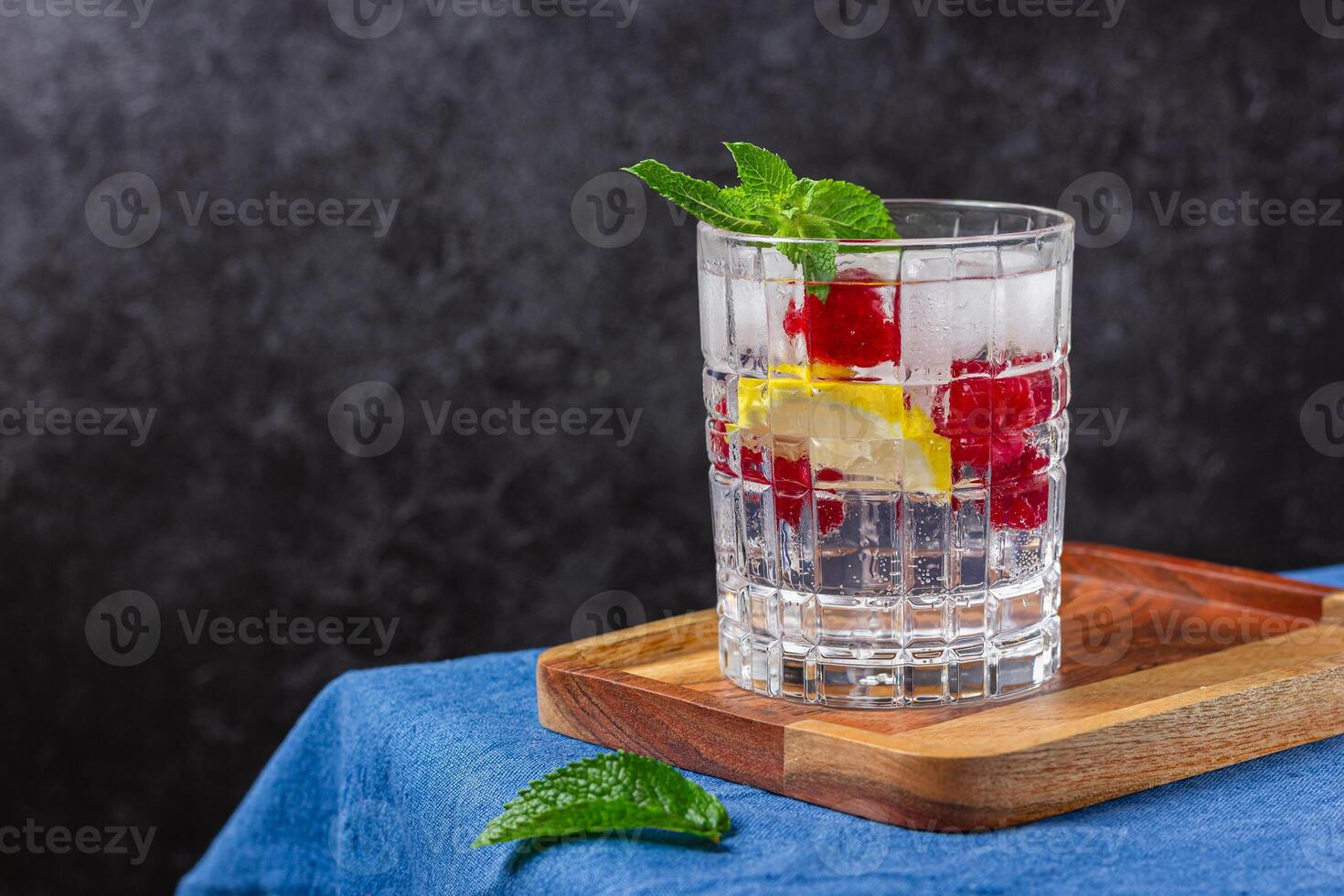 Raspberry cocktail with ice in a glass on a wooden tray photo