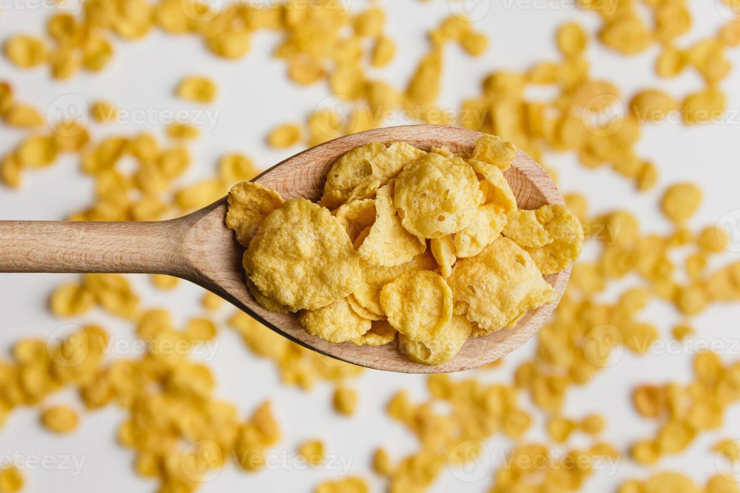 Corn flakes on wooden spoon white background. photo
