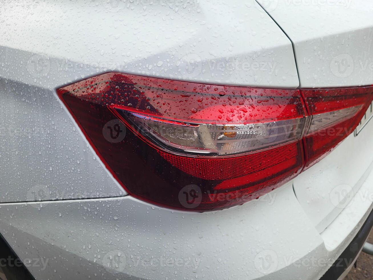 Red taillight of a white car with raindrops. photo