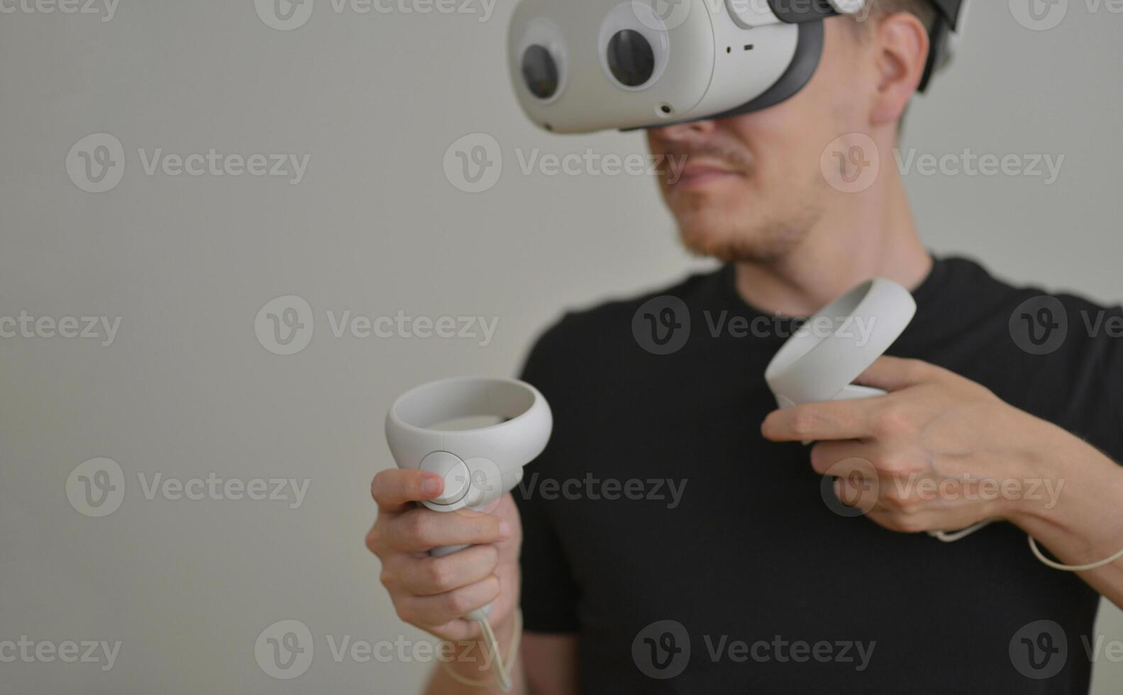 A Young Man Playing using Visual Reality Glasses with eye stickers. VR Headset Goggles Connecting Metaverse with Joysticks. Futuristic Cyberspace Technology, Virtual Digital Environment Concept photo