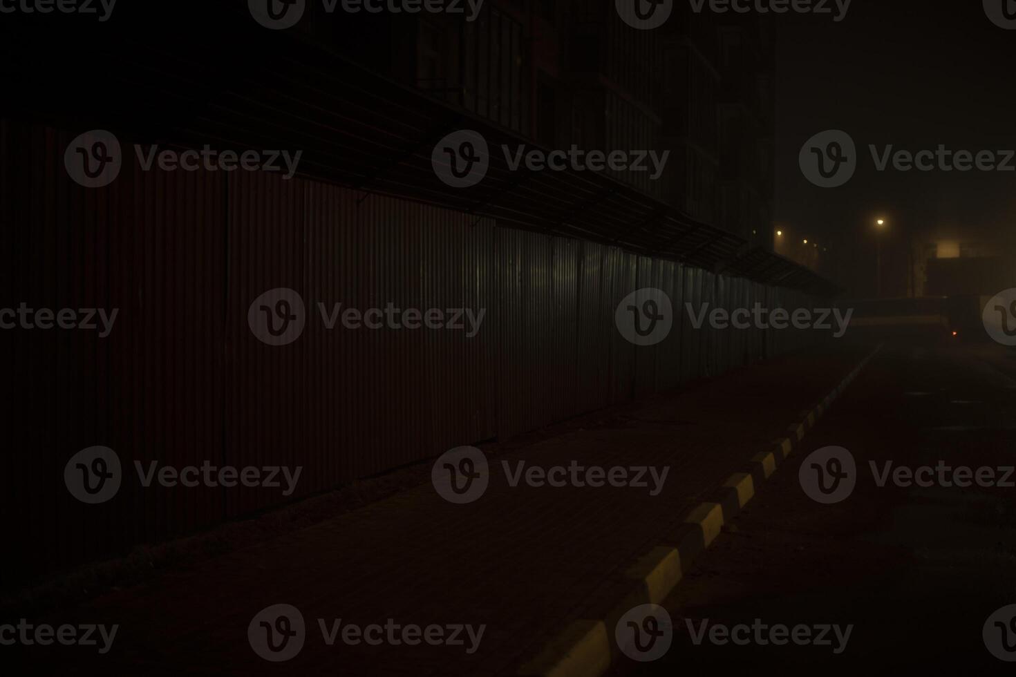 Fence at night. Driving between houses in dark. Evening city without people. photo