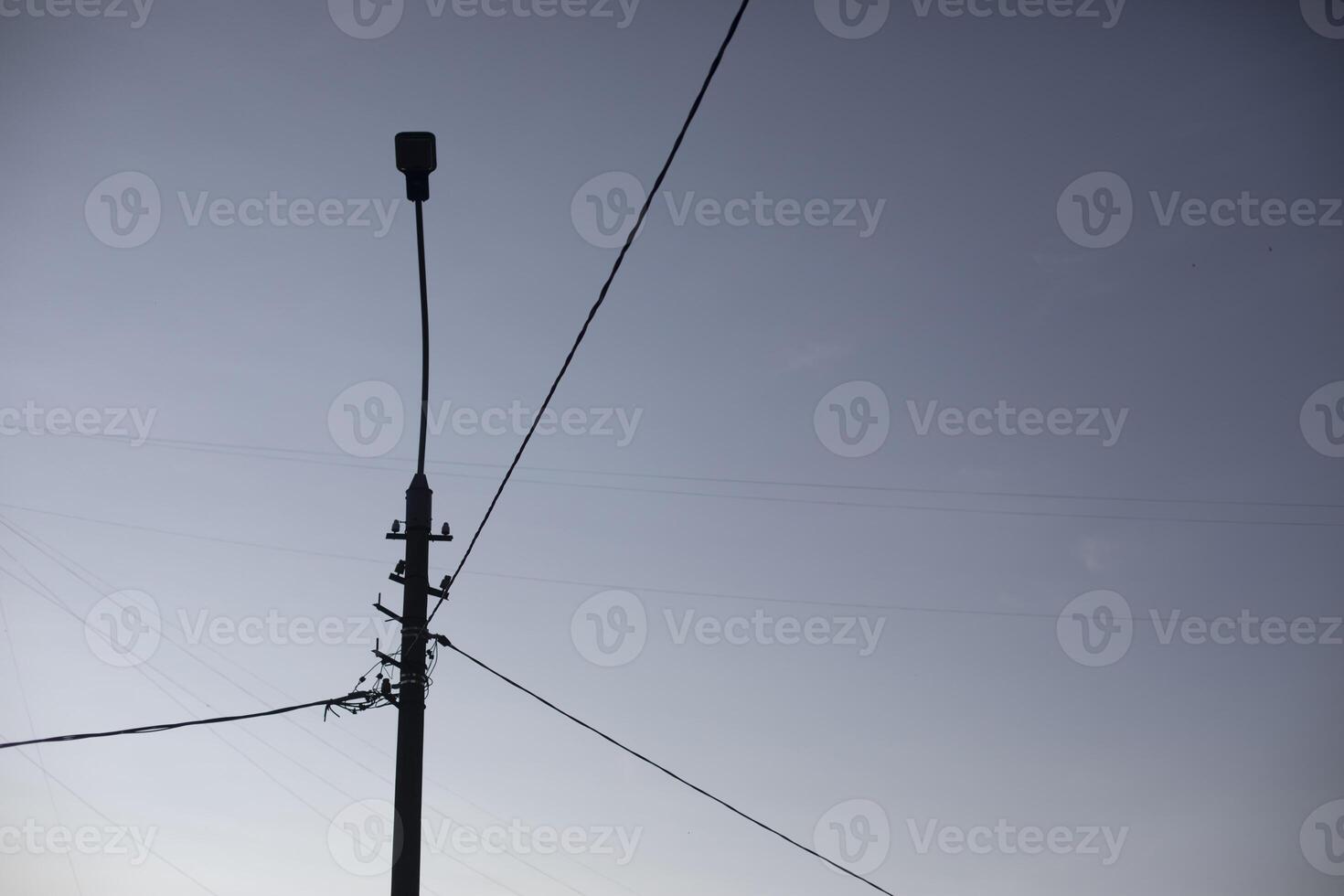 Stob with wires. Street pole with light. Silhouette of an electric lamp on the street. photo