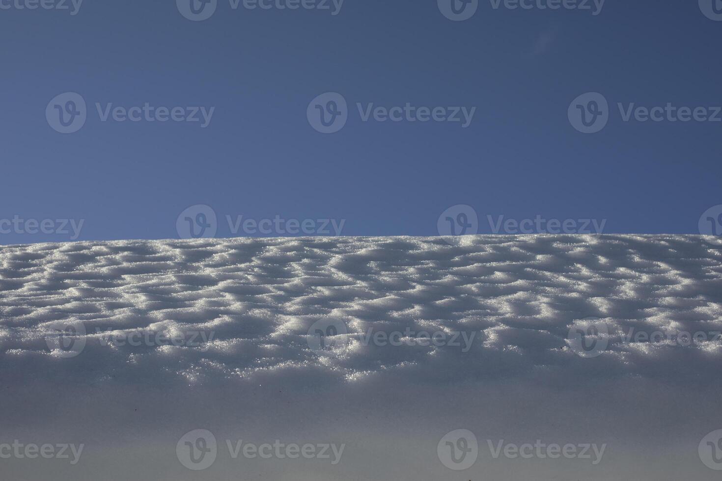 The snow on the roof. Snow and sky. Melting of the snow layer. photo