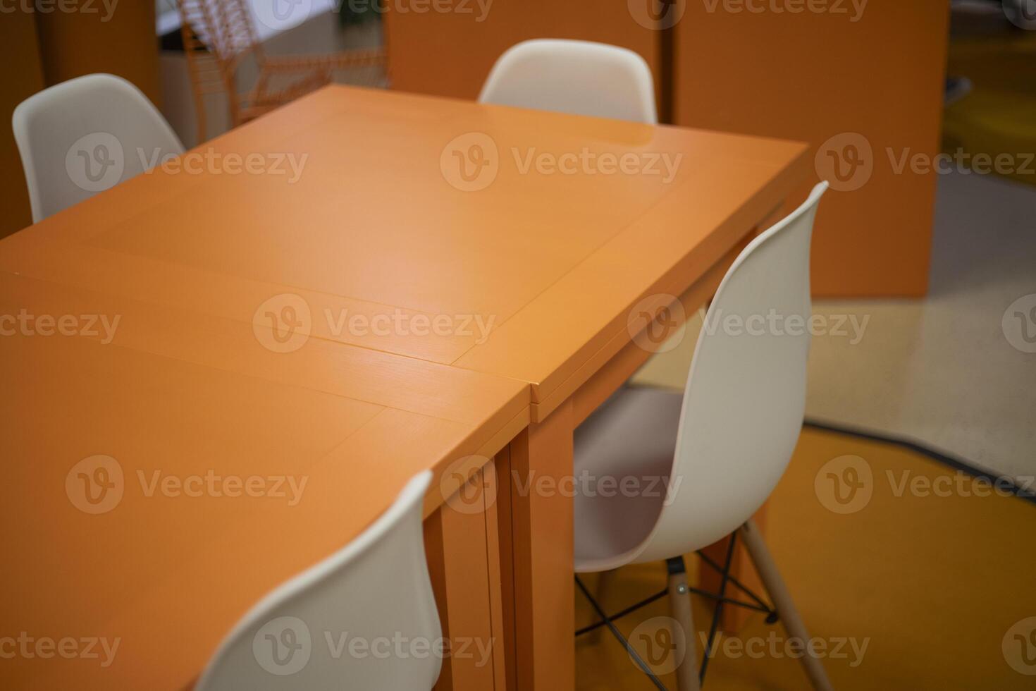 Orange table in the interior. A place to learn. White chairs. photo