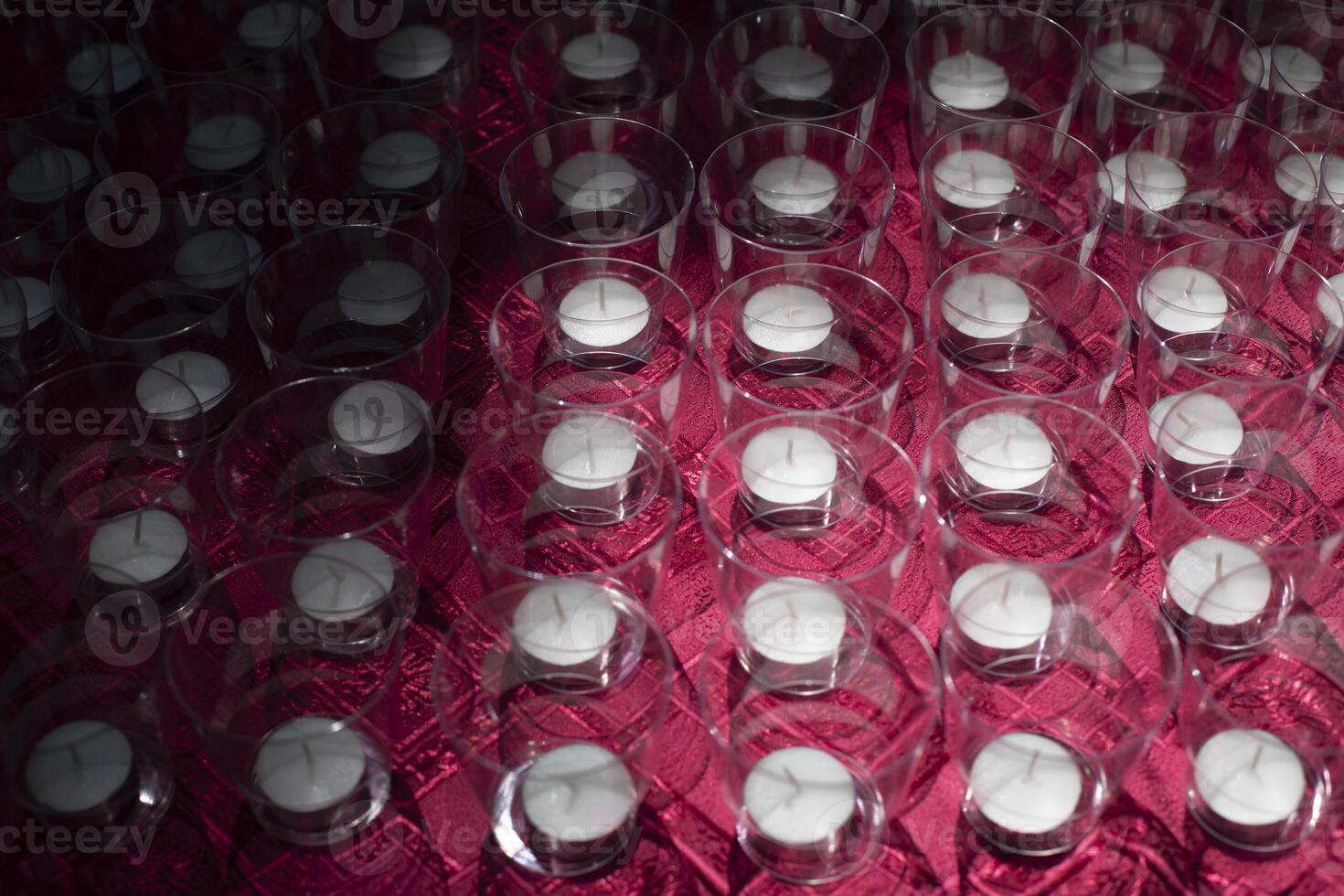 Candles in glasses. Lots of candles on table. Texture of transparent cups. photo