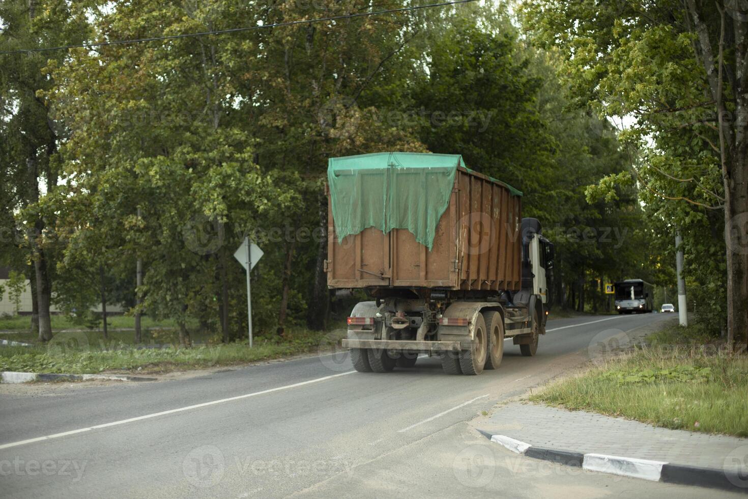 Garbage truck. Transportation of waste in summer. Truck on road. Large container of garbage. photo