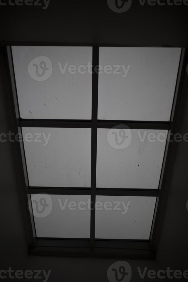 Large window in the ceiling. Faint light through glass. Grey day outside the window. photo
