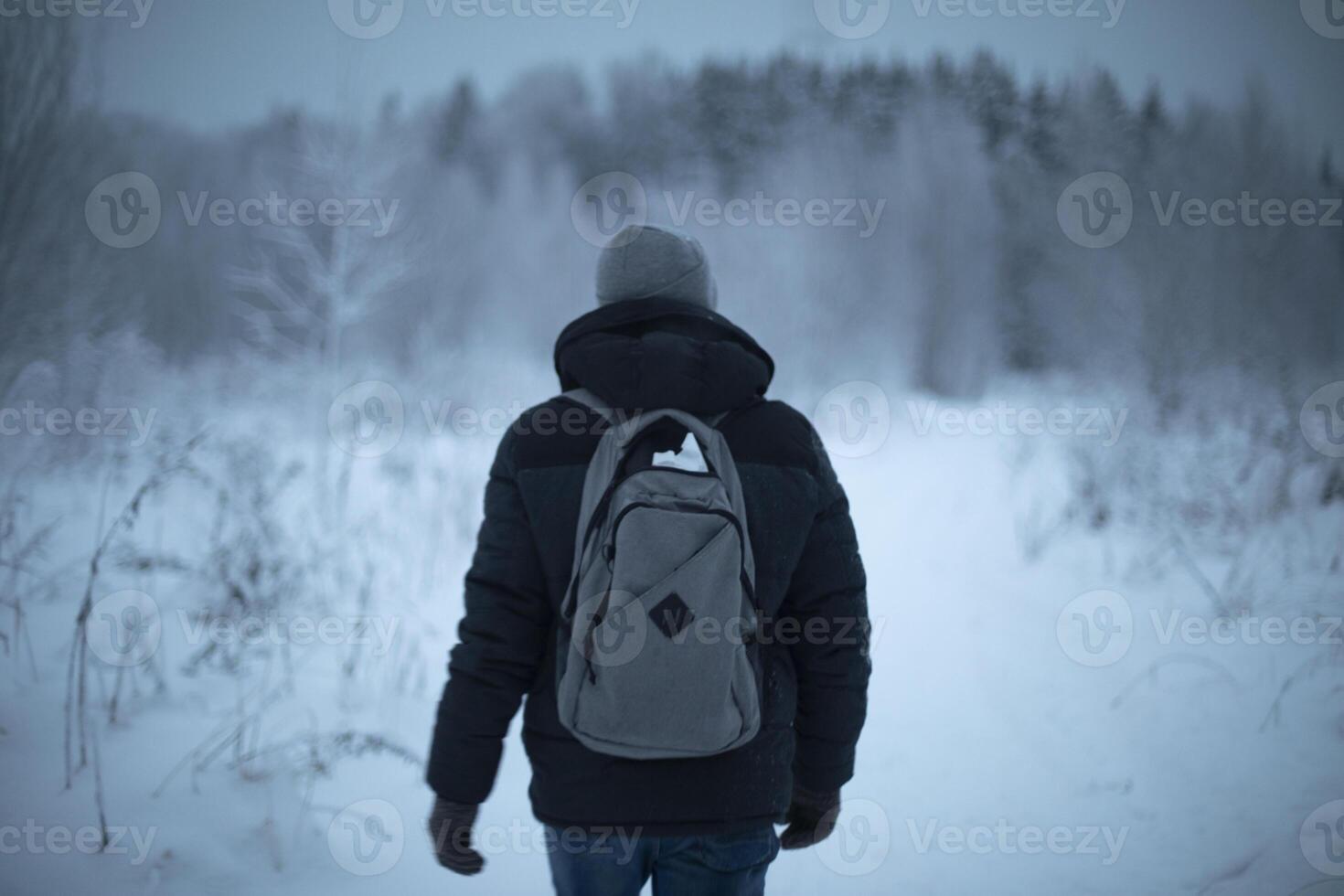 Guy with backpack in winter. Man walks through woods in cold. Middle-aged man in warm clothes. photo