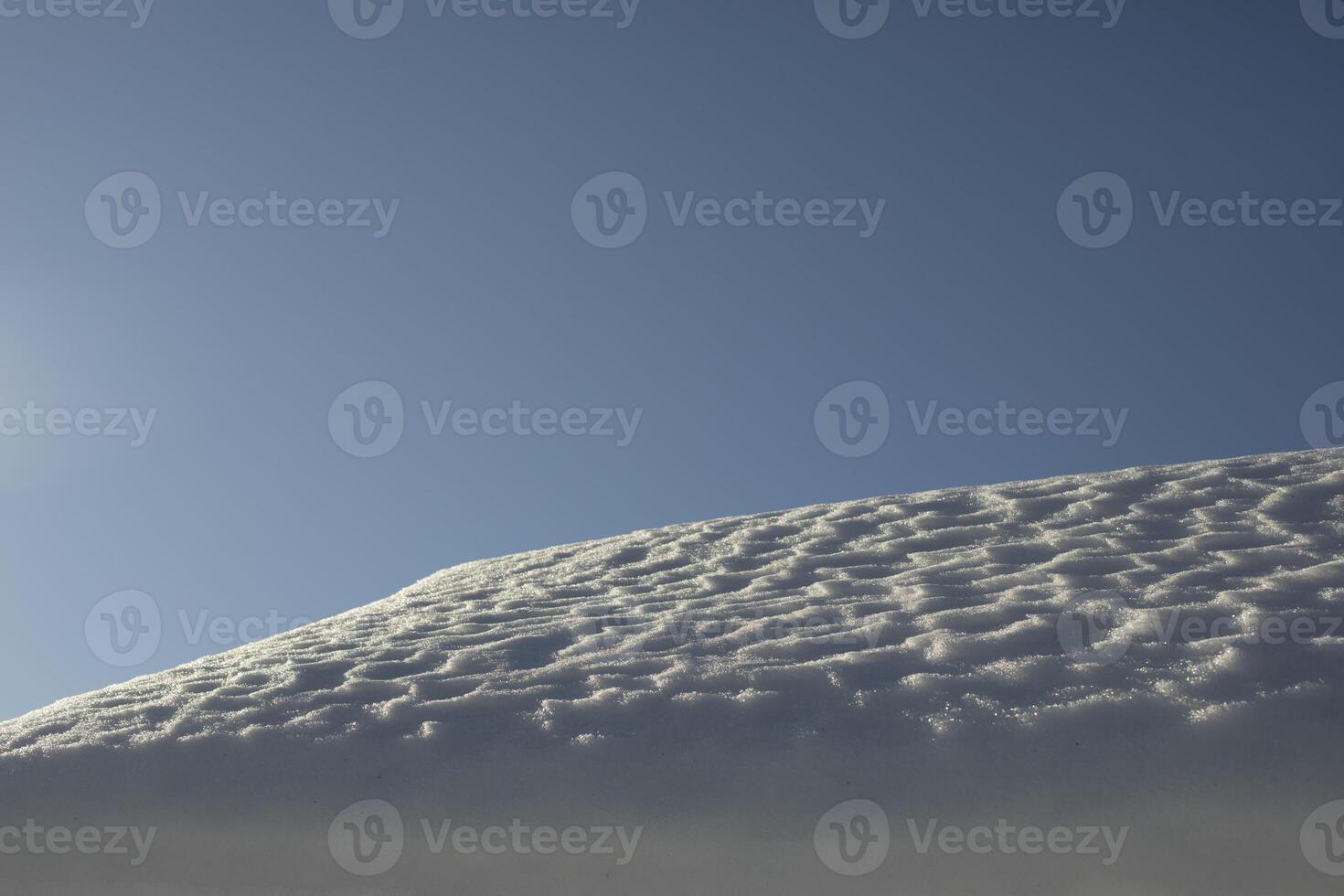 The snow on the roof. Snow and sky. Melting of the snow layer. photo