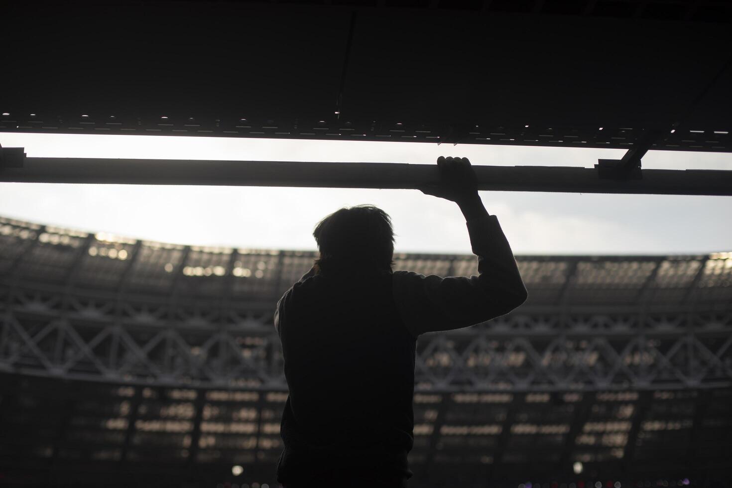 Guy at stadium. Silhouette of man against background of stadium. Mass event and one person. photo