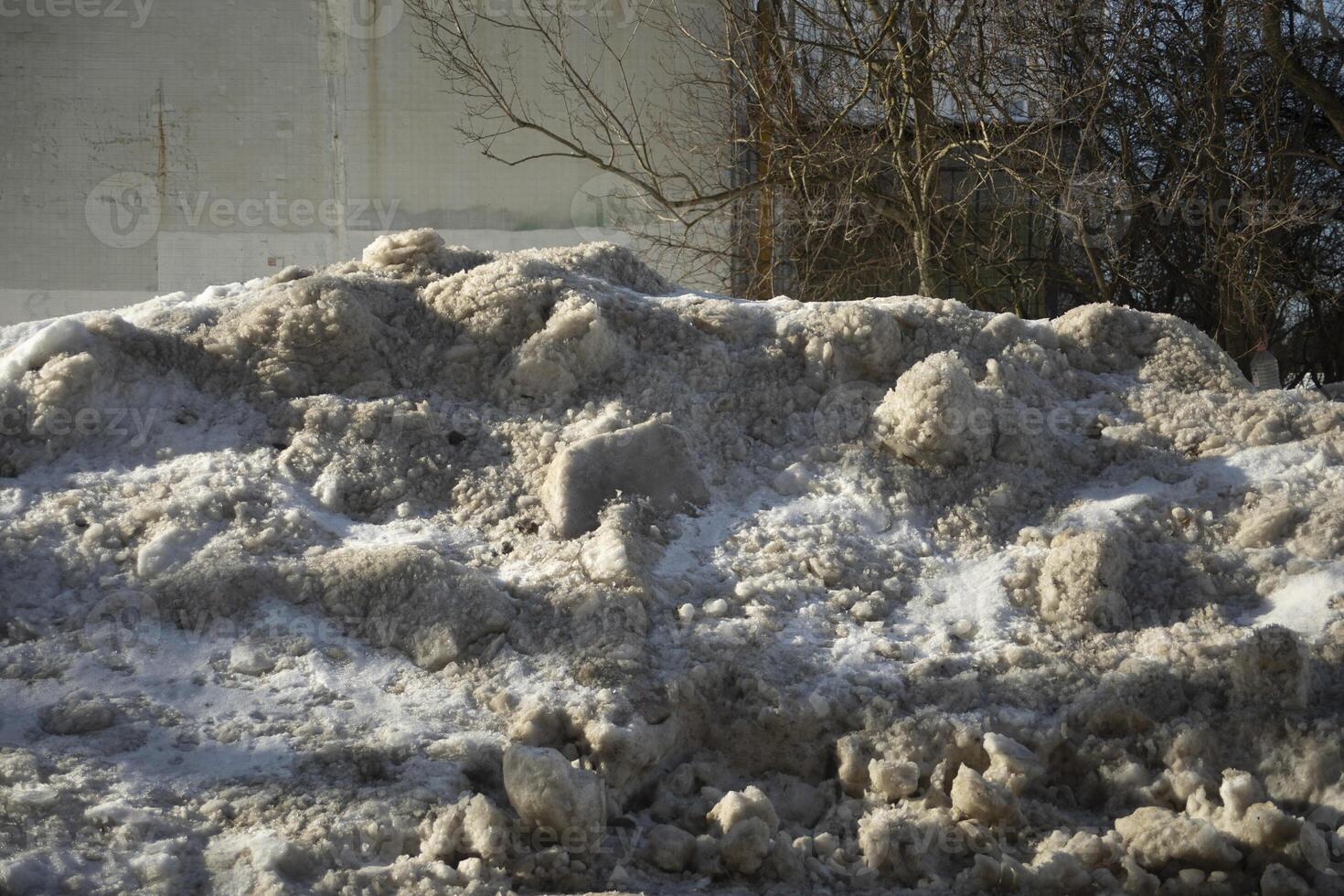 Dirty pile of snow in the city. Removing snow from the road. Dirty sand. photo