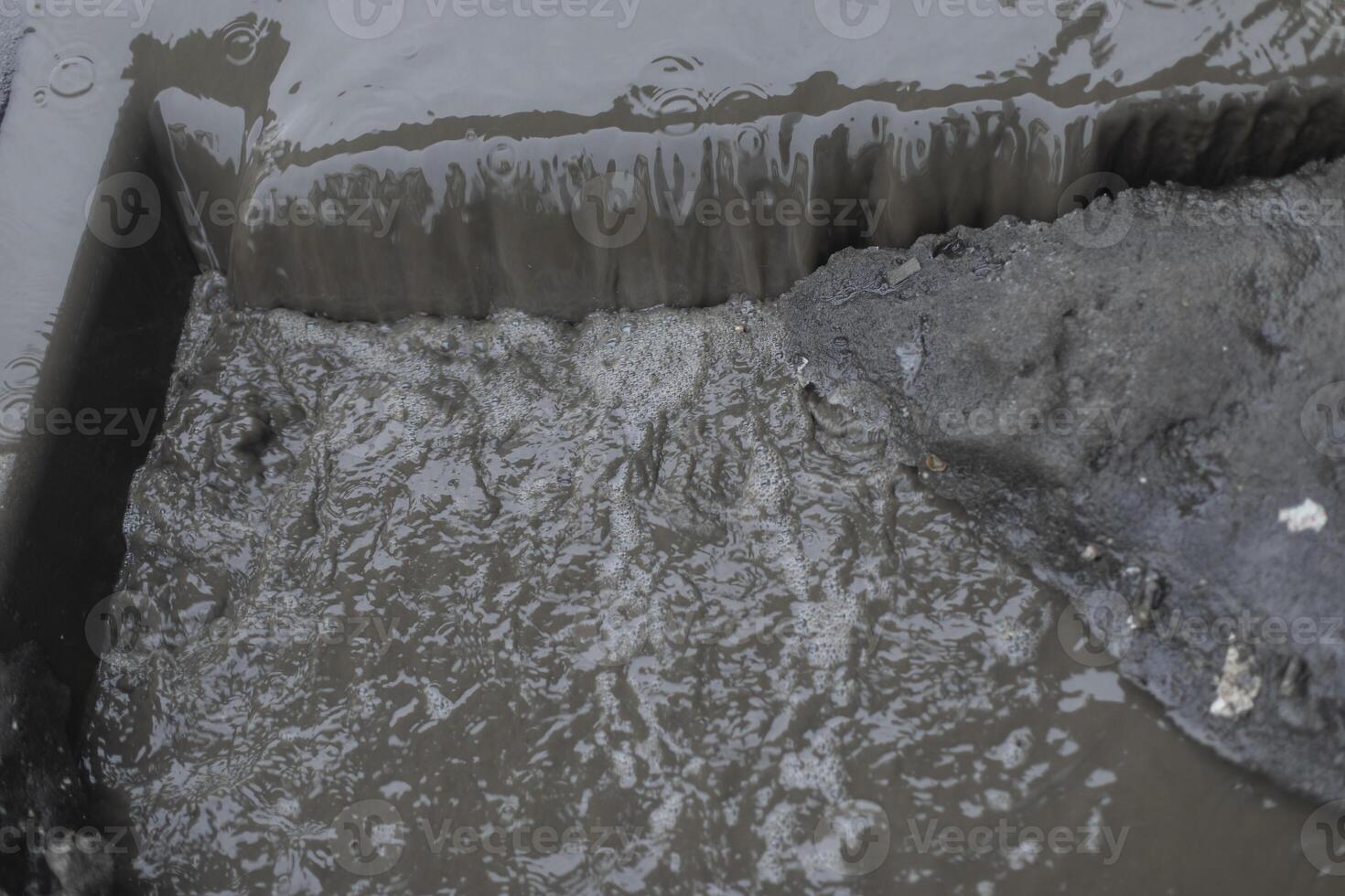 Dirty water flows on asphalt. Flow of water along road. Cloudy liquid. photo