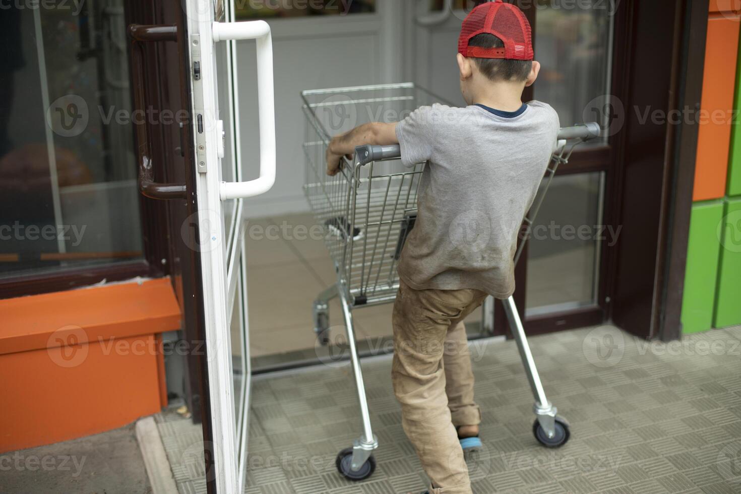 Child takes cart out of store. Boy indulges in supermodel. Schoolboy steals cart for groceries. photo