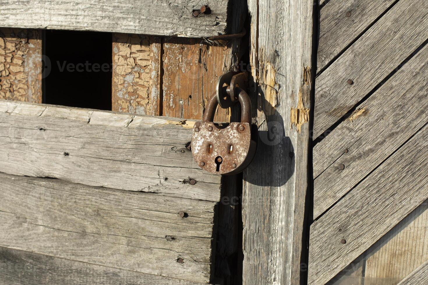 Old lock on the door. Rusty lock on the barn. The old building in detail. photo