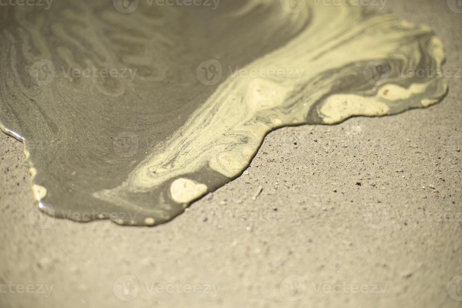 Pollen in water. Yellow pollen from plants. Puddle on pavement. photo