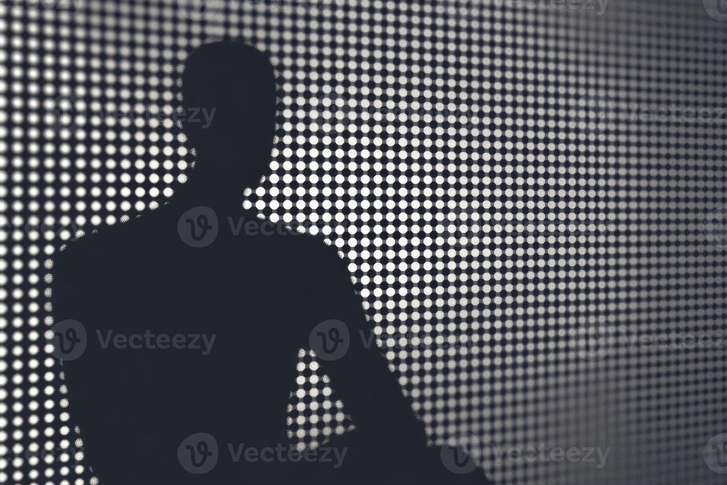 Silhouette of a man sitting on a chair in front of a wall with dots photo