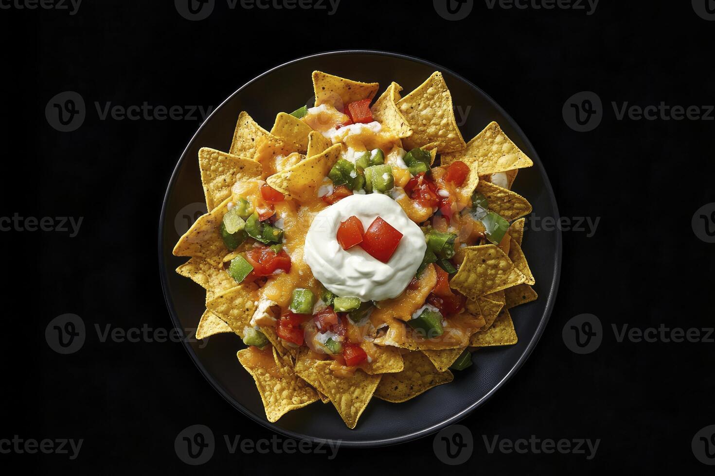 Nachos with sour cream and vegetables on a black plate photo