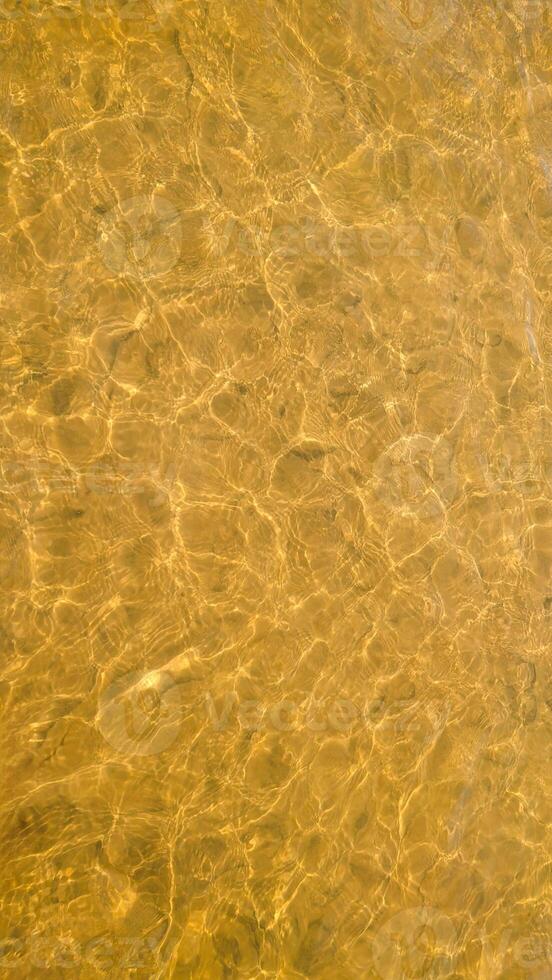 Vertical abstract background. Golden river water surface with sun reflections photo