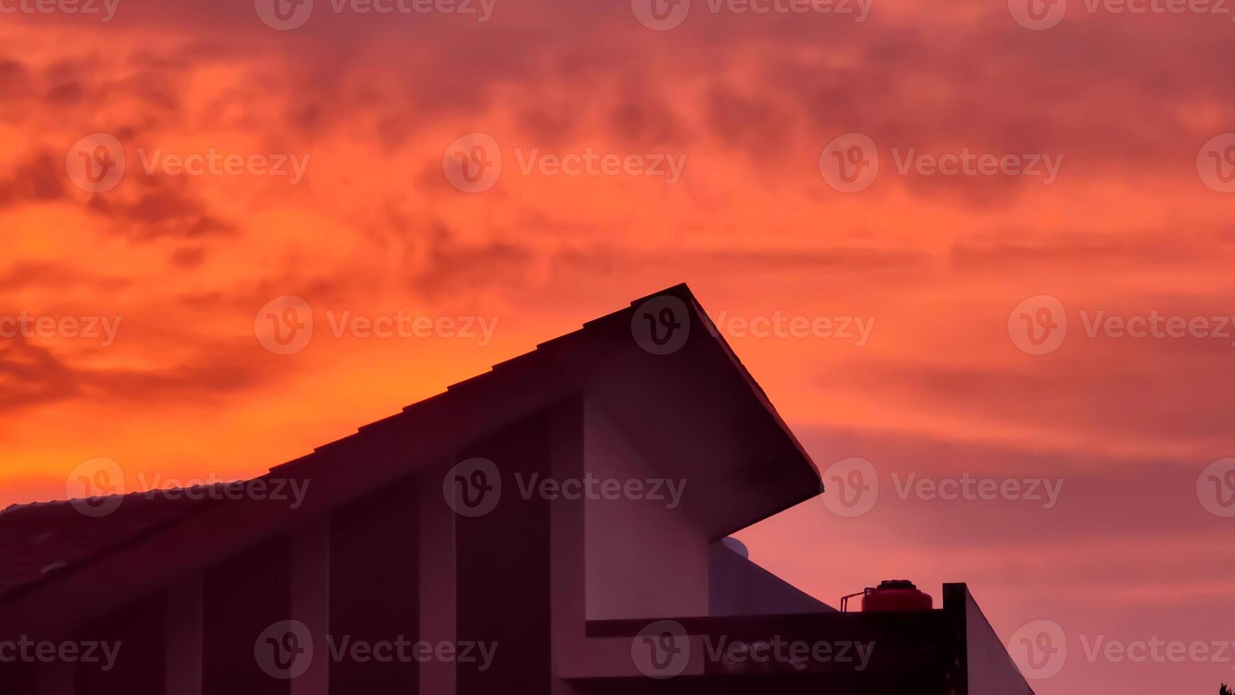A red sky with clouds and a house in the foreground photo