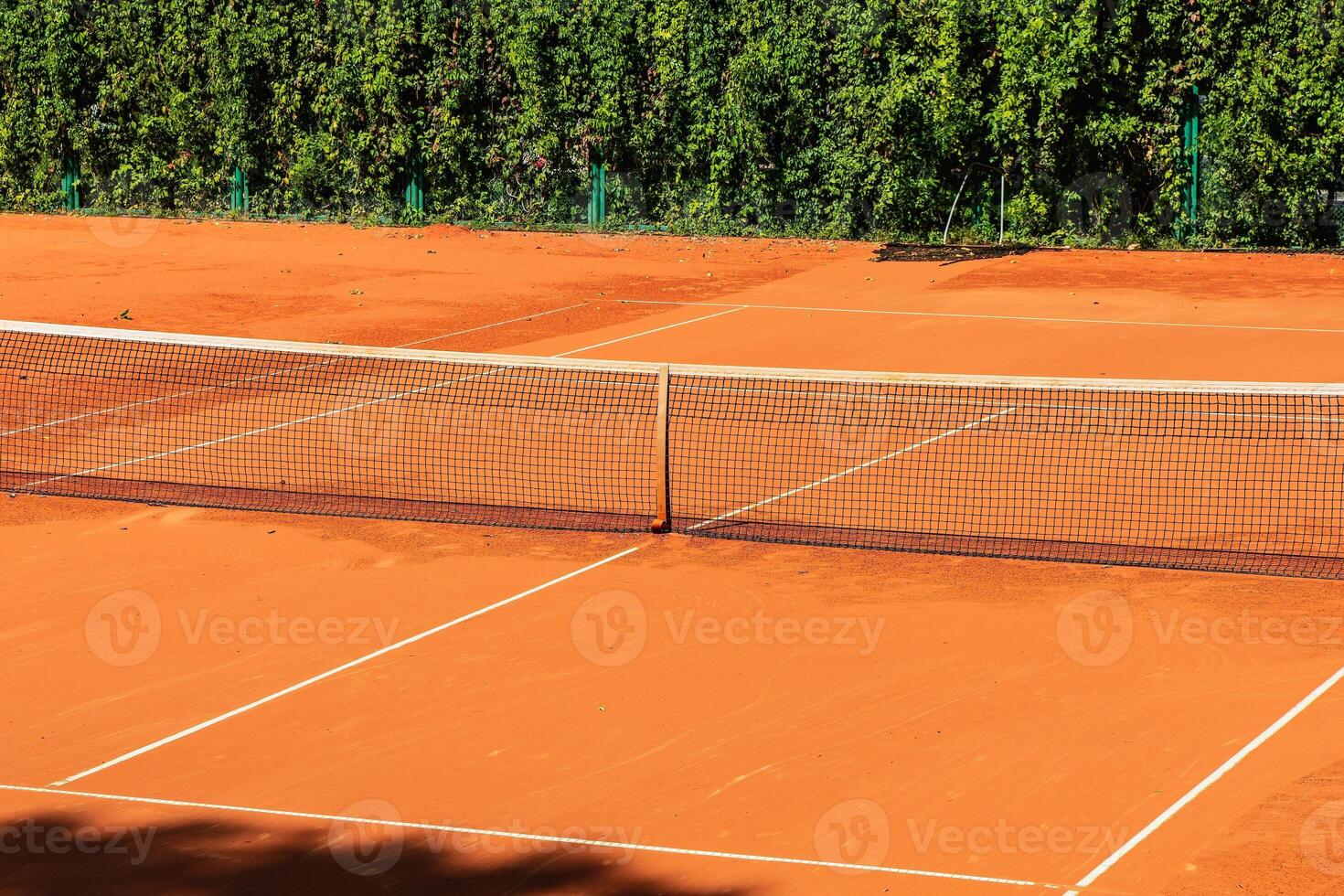 Tennis court with a sand surface and a stretched net for playing a sports game with a ball and rackets photo
