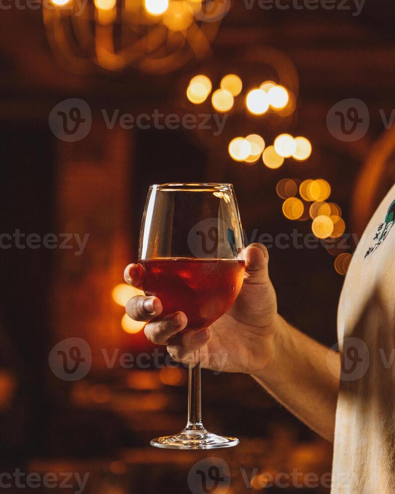 Man holding a glass of wine in a warmly lit bar photo