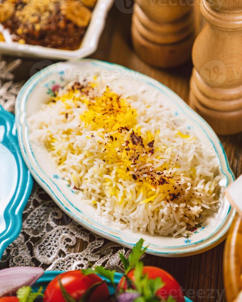 Saffron rice being served on floral plate on a rustic table setting photo