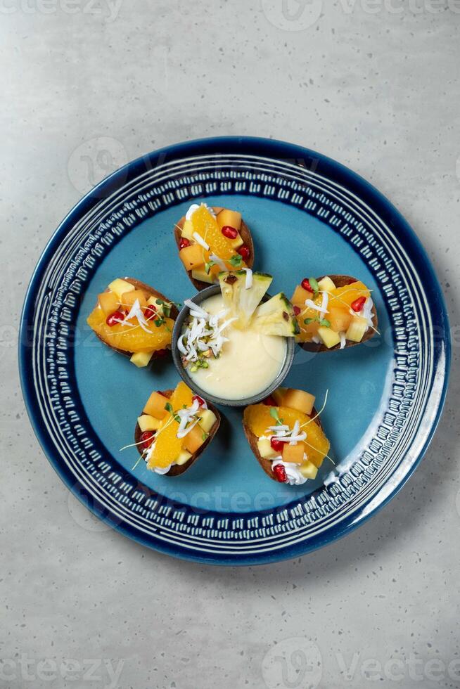 Delicious fruit salad serving on blue plate on table photo