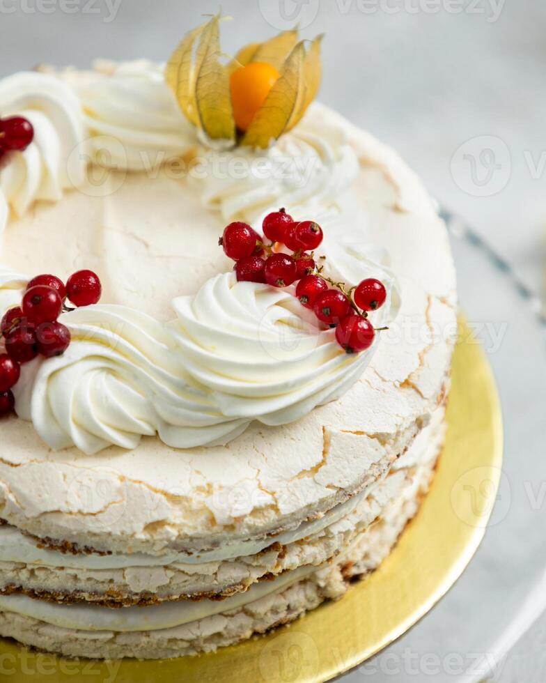 Delicious meringue cake decorated with red currants and physalis photo