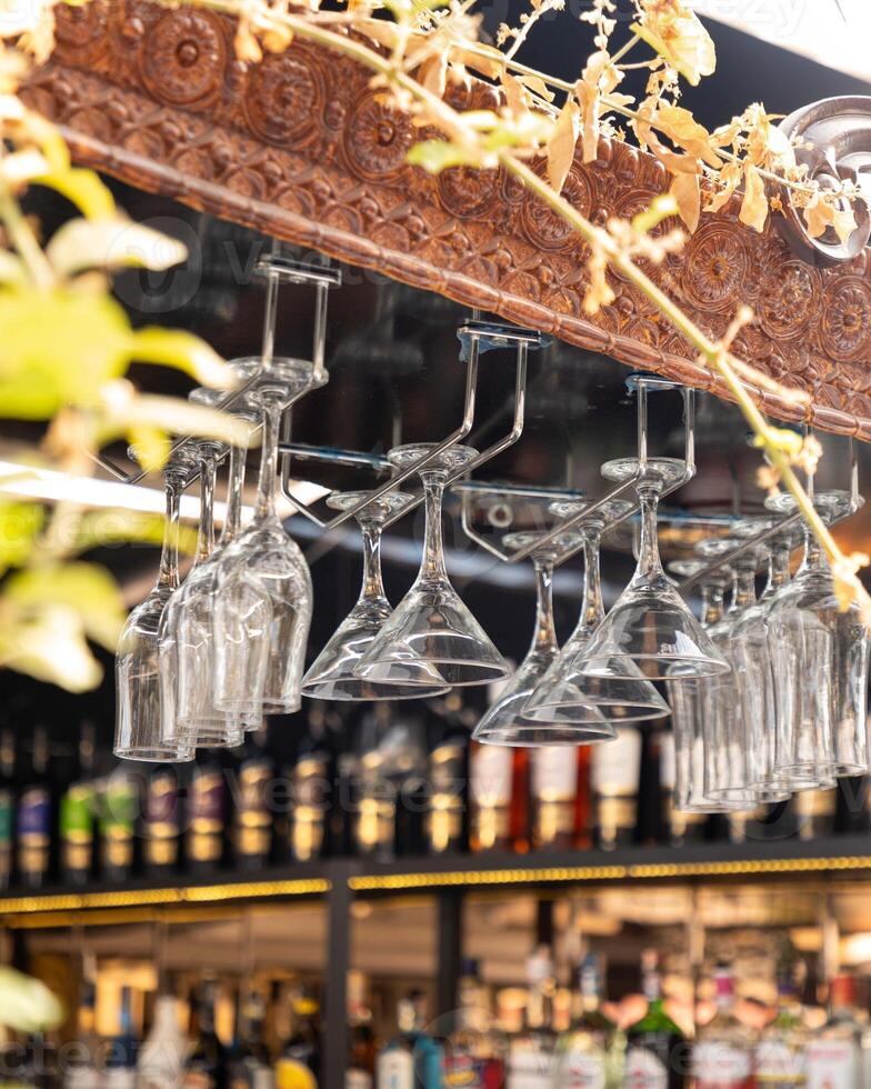 Empty wine glasses hanging over a bar, waiting for customers to arrive photo