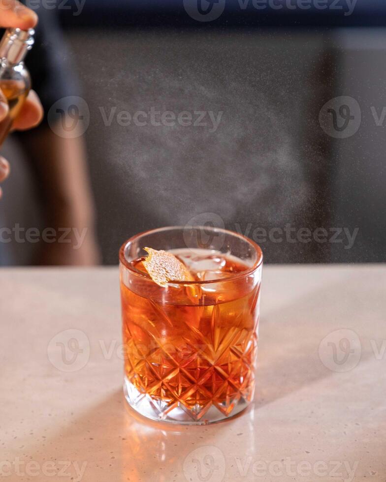 Bartender spraying on cocktail garnish with atomizer in bar setting photo