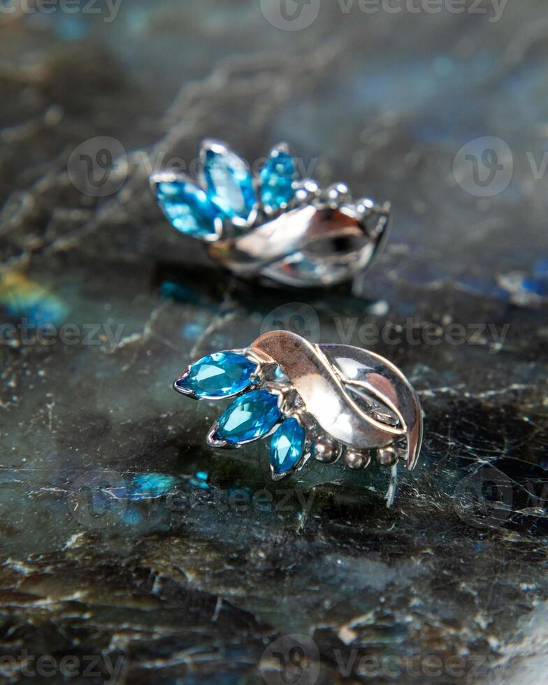 Silver earrings with blue topaz sparkling on dark background photo