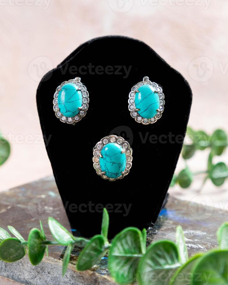 Silver jewelry set with turquoise stone on black display stand photo