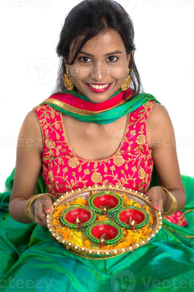 Portrait of a Indian Traditional Girl holding Diya, Girl Celebrating Diwali or Deepavali with holding oil lamp during festival of light on white background photo