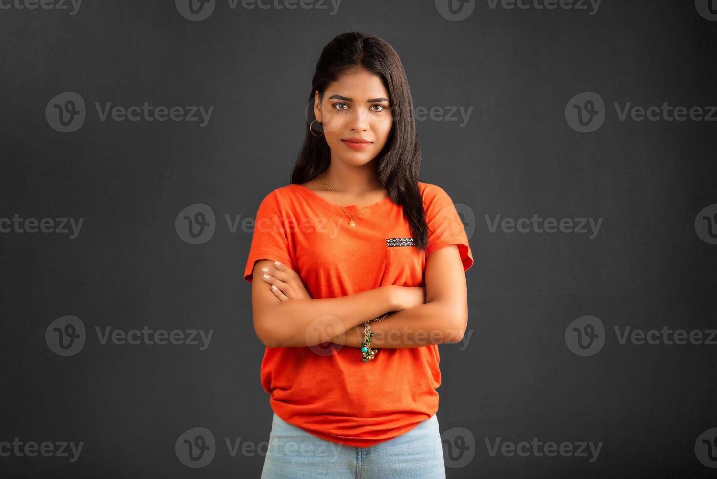 Portrait of a beautiful, smiling, young girl posing with hands-folded on gray background. photo