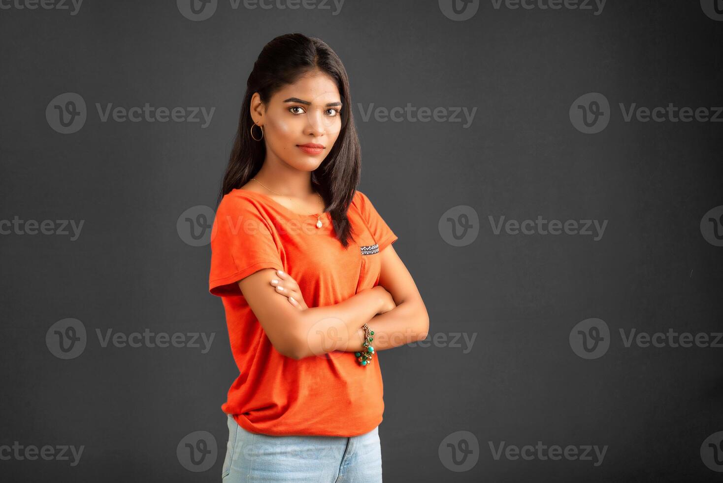 Portrait of a beautiful, smiling, young girl posing with hands-folded on gray background. photo