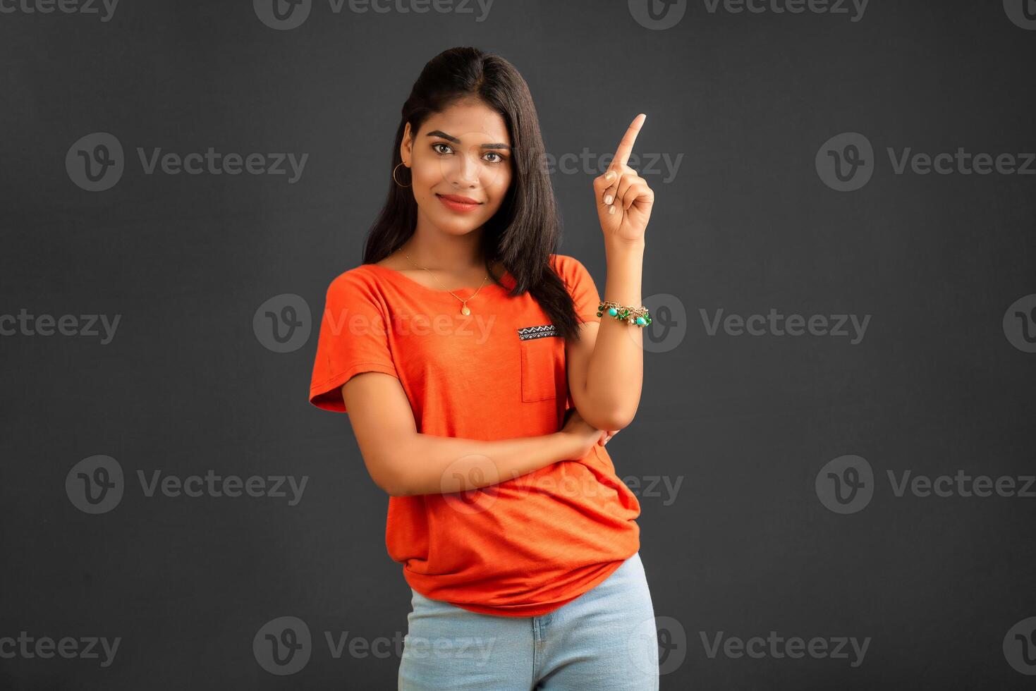 Portrait of a successful cheerful young girl pointing and presenting something with hand or finger with a happy smiling face. photo